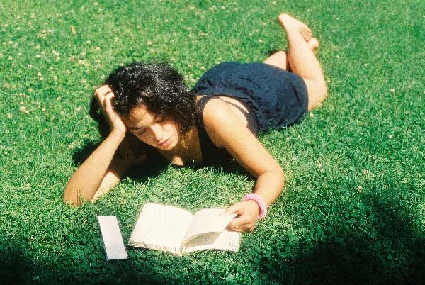 Retrato de una mujer leyendo en el césped